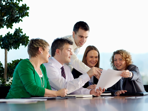 Un grupo de empleados charlando en una gran mesa de reuniones.