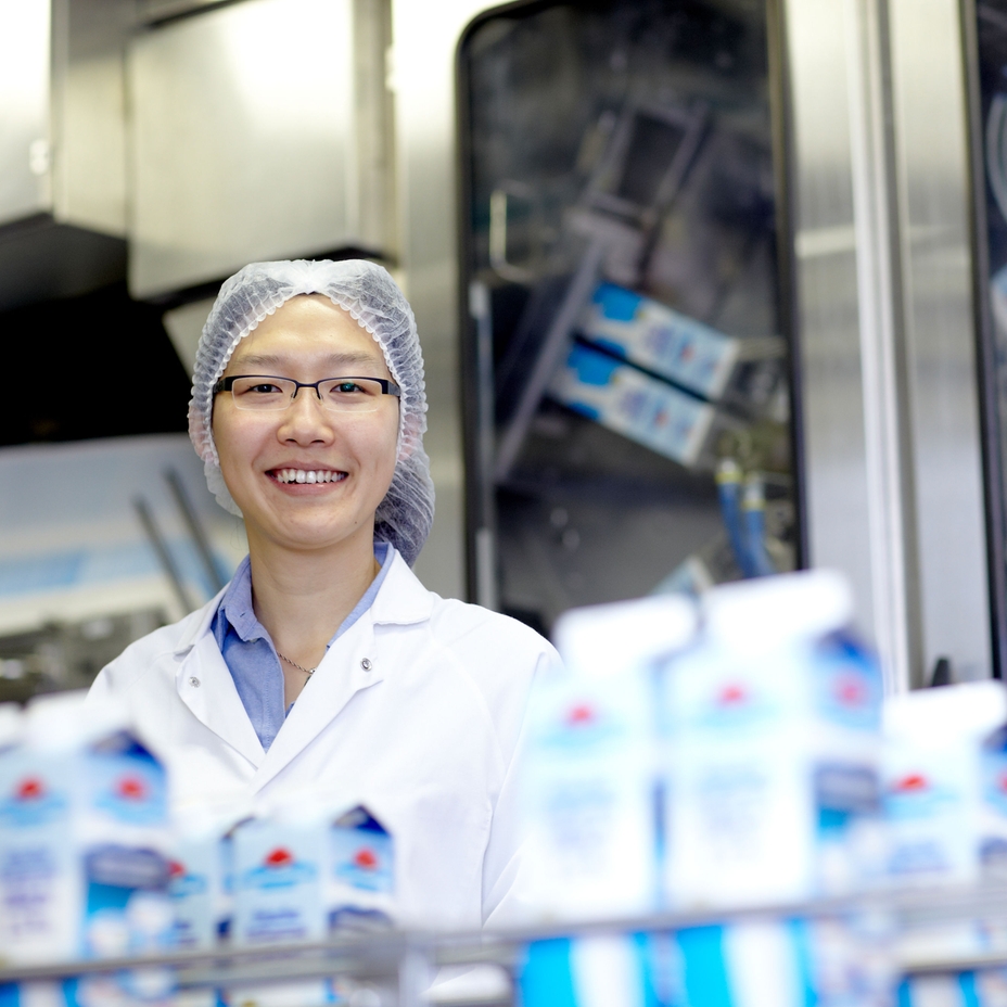 Una mujer de pie en una planta de procesamiento de leche