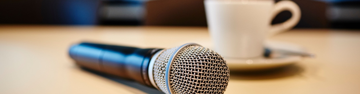 Modo conferencia de prensa: micrófono y taza de café sobre la mesa.