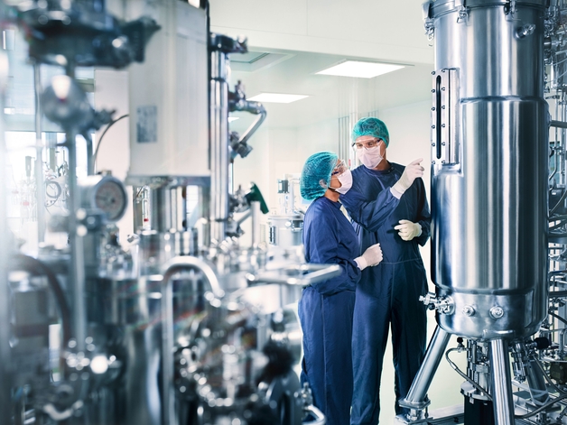 Dos técnicos en un entorno de proceso farmacéutico higiénico.